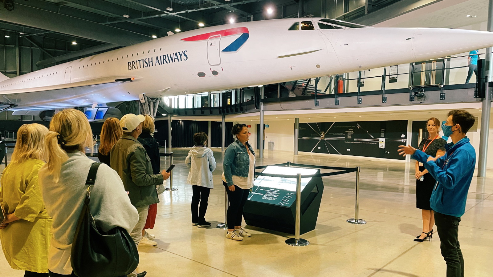 Man talking to group of people under Concorde at Aerospace Bristol